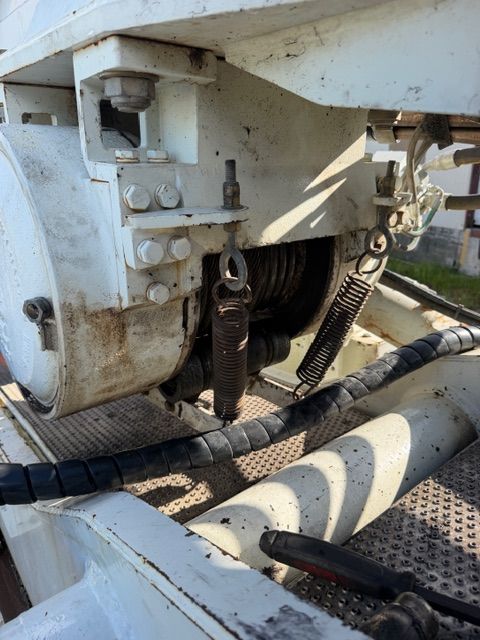 Close-up of a heavy machine hitch with chains and hoses on a metal platform, with some rust and dirt.