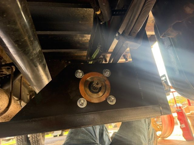 Undercarriage mechanical assembly with a bronze wheel bearing mounted on a black metal bracket