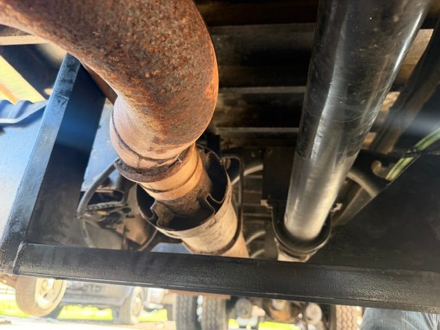 Rusty and black vehicle undercarriage with exhaust pipes and frame visible