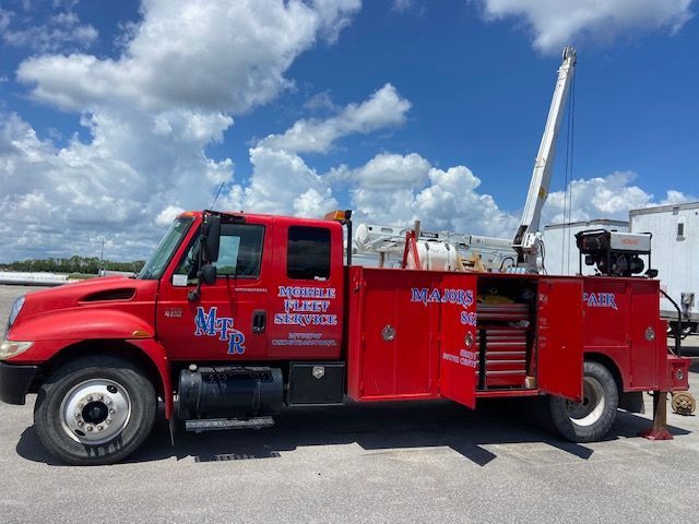 A red tow truck with the doors open is parked in a parking lot.