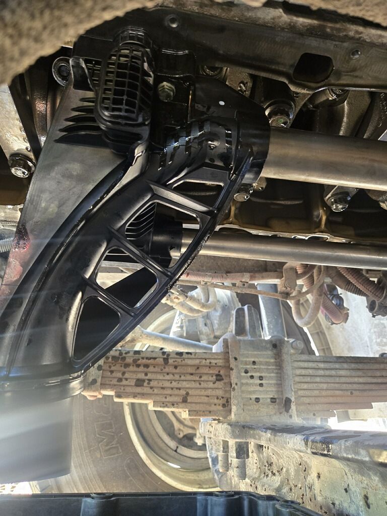 Undercarriage of a vehicle with a black suspension arm and wheel visible in a garage lift area