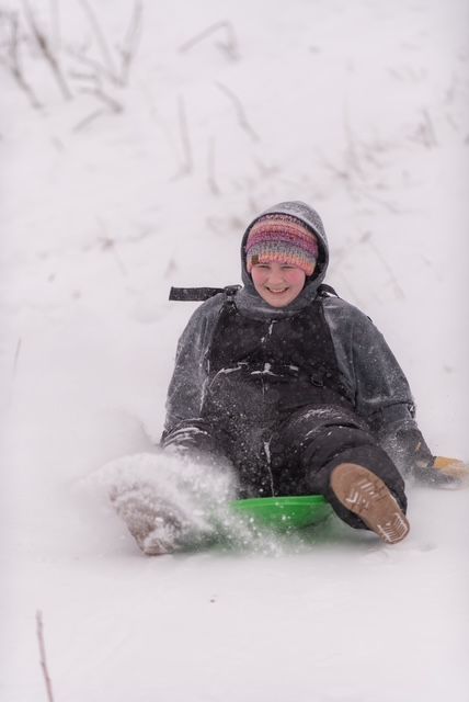 A person is sliding down a snow covered hill on a sled.