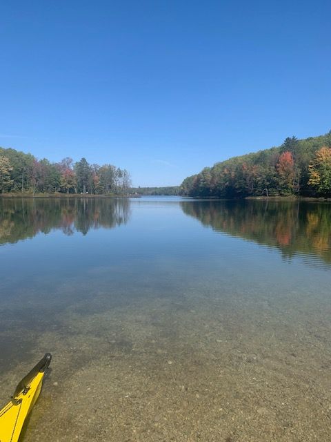 A yellow kayak is sitting on the shore of a lake.