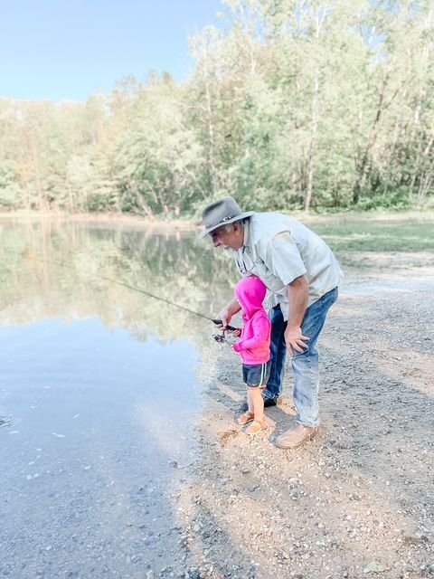 A man and a little girl are fishing in a lake.