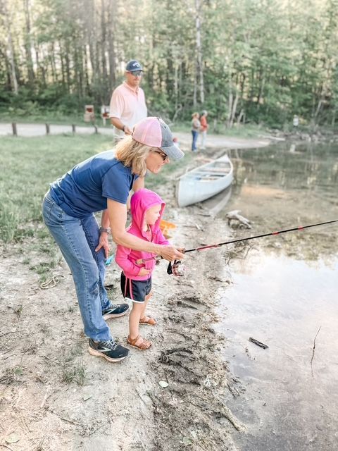 A woman and a little girl are fishing in a lake.