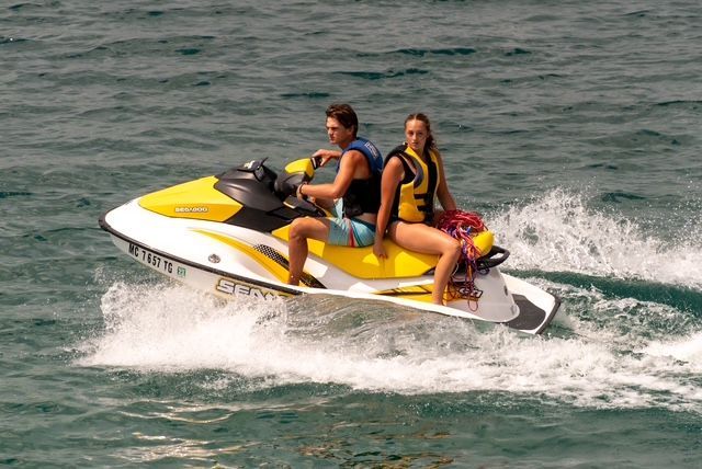 A man and a woman are riding a jet ski in the ocean.