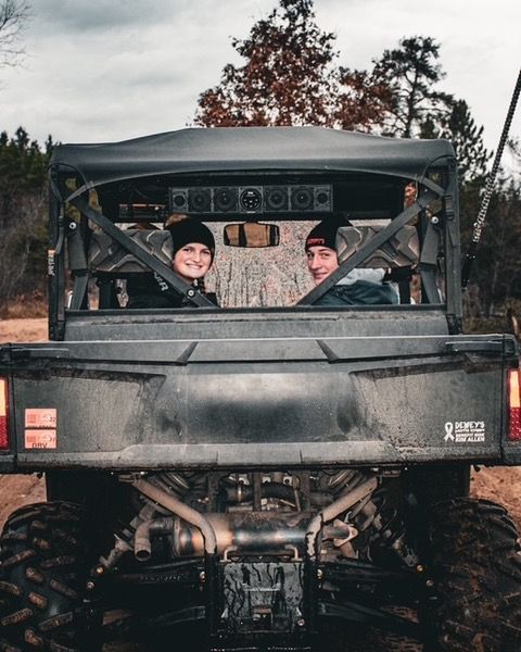 Two people are sitting in the back of a truck.