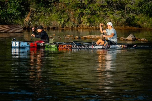 Two men are fishing in a canoe on a lake.