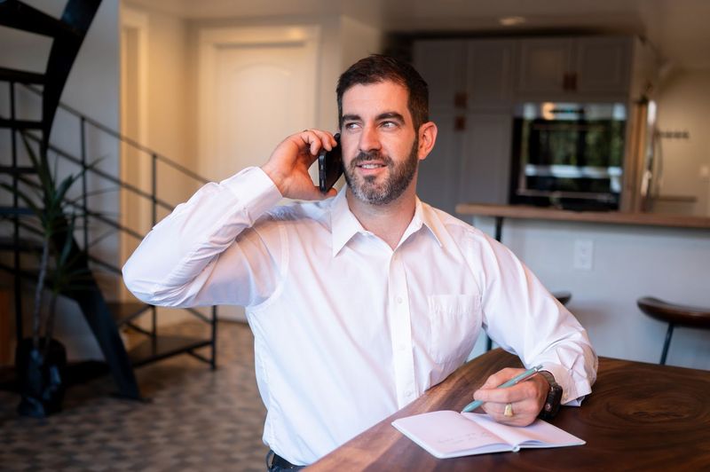 Evan on a phone call at a walnut table