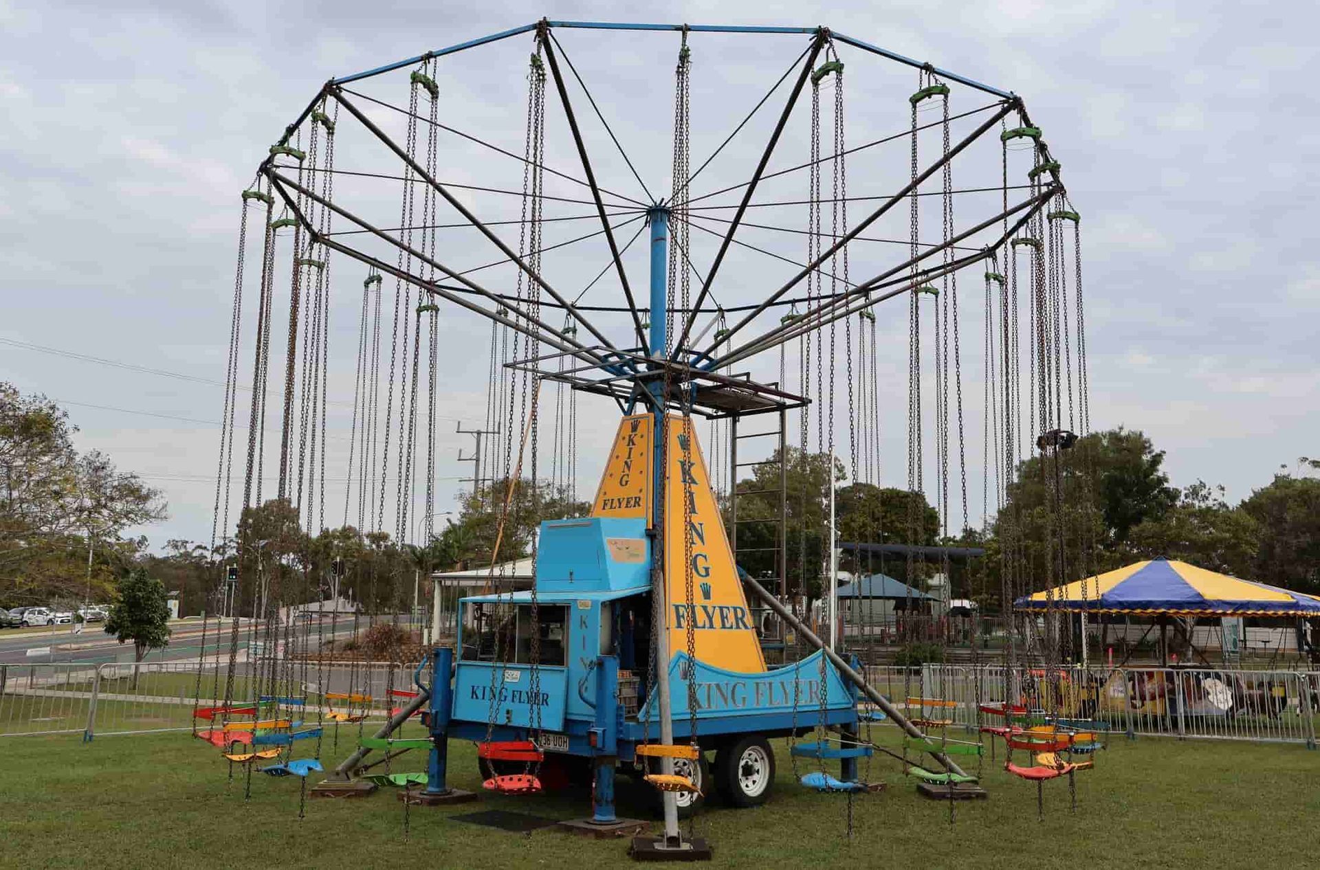 A Blue And Yellow Carnival Ride Is Sitting In A Grassy Field — Bills Amusements In Emerald, QLD