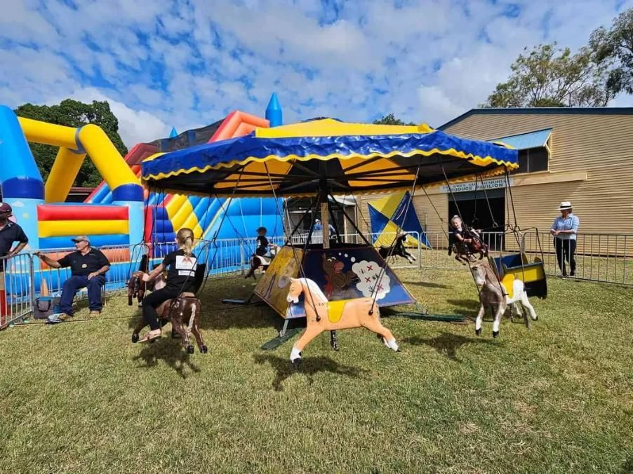 A Group Of People Are Riding A Merry Go Round In A Park — Bills Amusements In Biloela, QLD