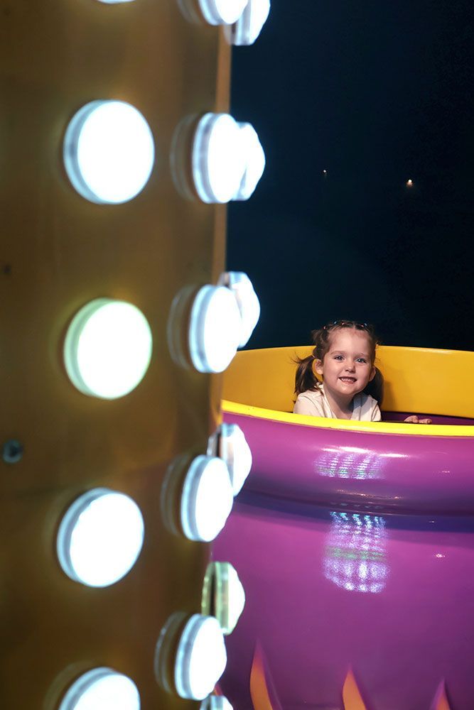 A Little Girl Is Sitting In A Purple Cup — Bills Amusements In Rockhampton, QLD