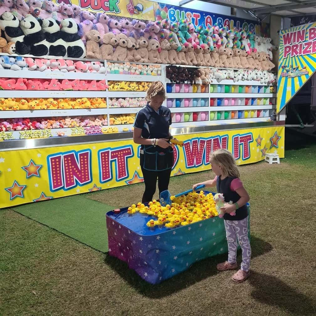 A Woman And A Little Girl Are Playing A Game At A Carnival — Bills Amusements In Gladstone, QLD