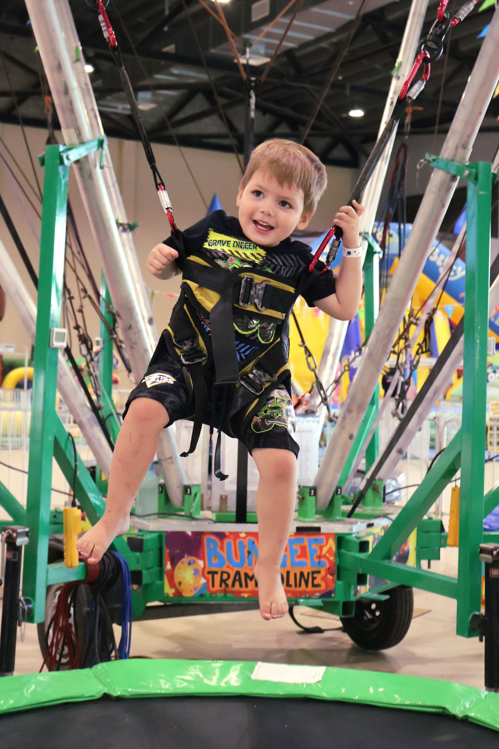 A Young Boy Is Sitting On A Green Trampoline — Bills Amusements In Rockhampton, QLD