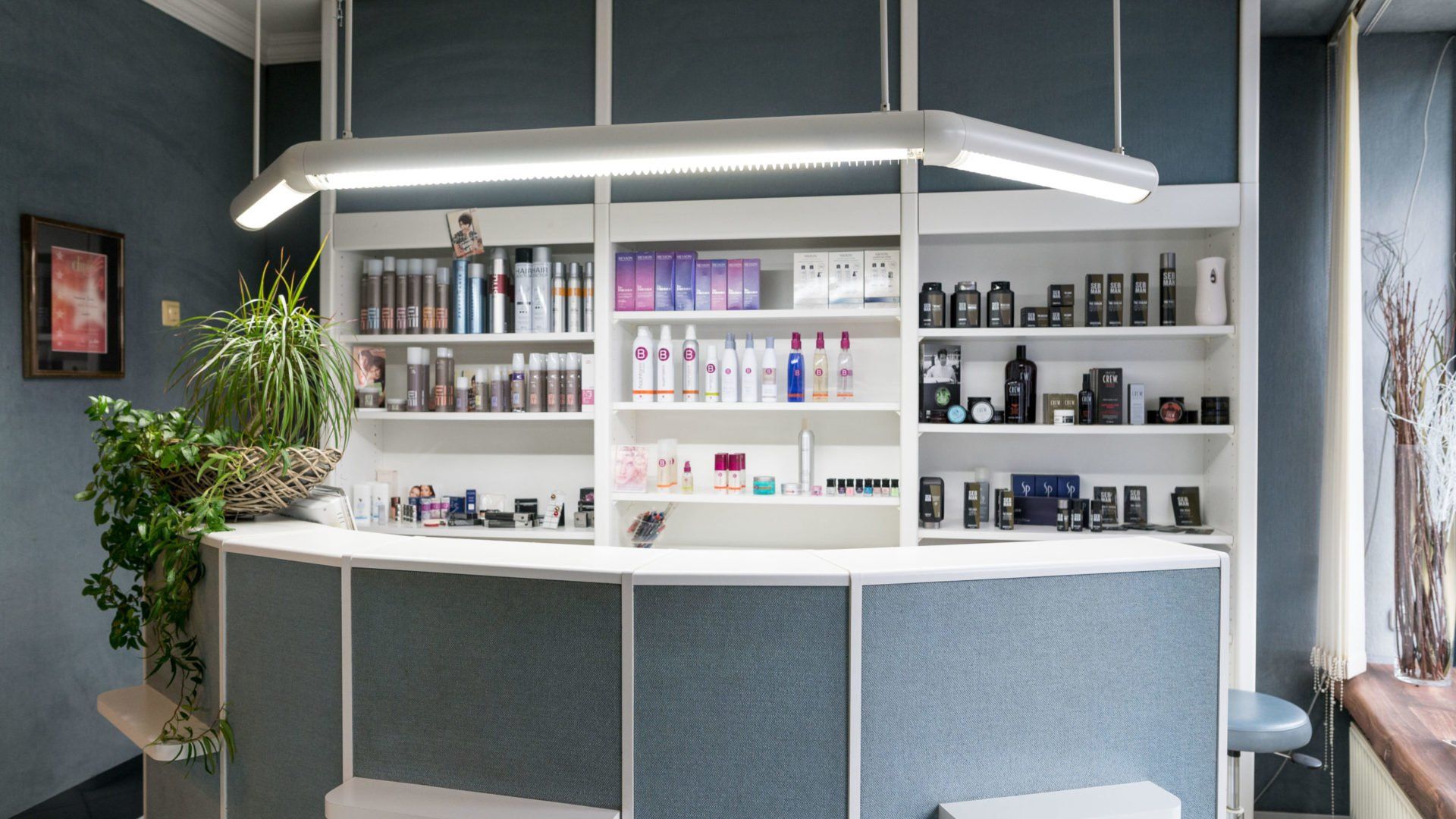 Empfangstresen in einem Salon mit Regalen voller Schönheitsprodukte. Weiße Regale und Theke, blaue 