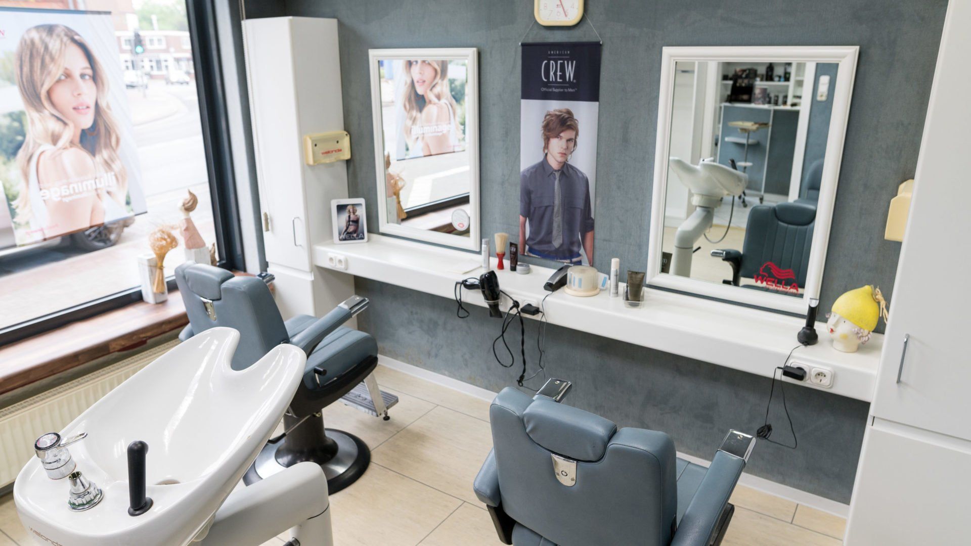 Inneneinrichtung eines Friseursalons mit Stühlen, Spiegeln und einem Waschbecken.