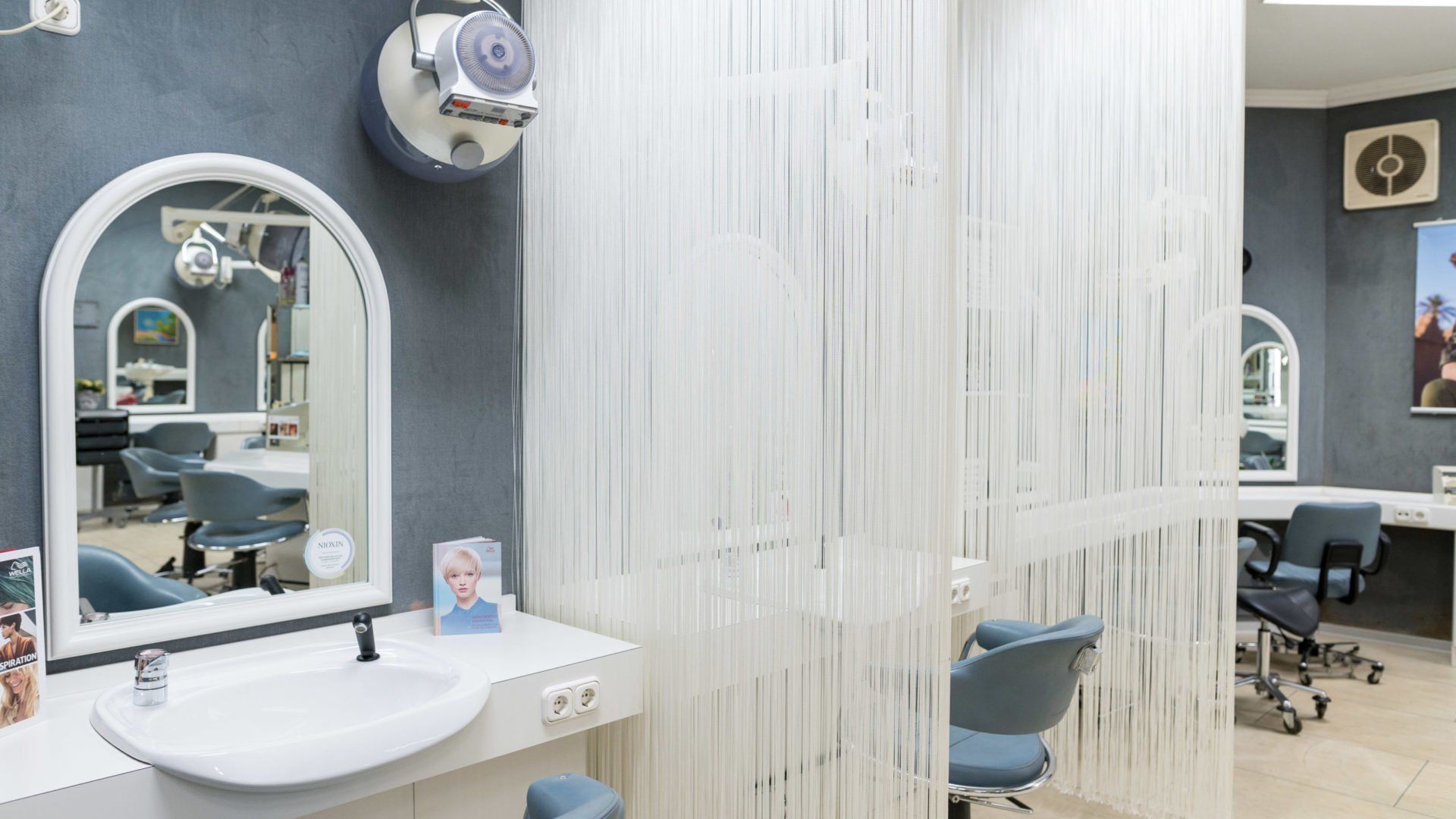 Inneneinrichtung eines Friseursalons: weißes Waschbecken, gewölbter Spiegel,