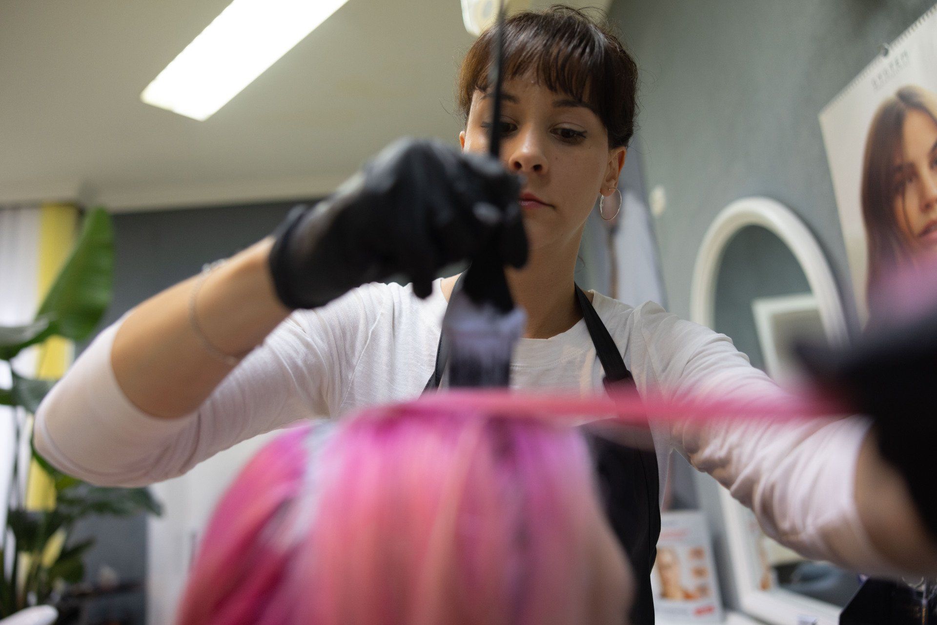 Friseur trägt mit einer Bürste rosa Farbe auf das Haar auf.