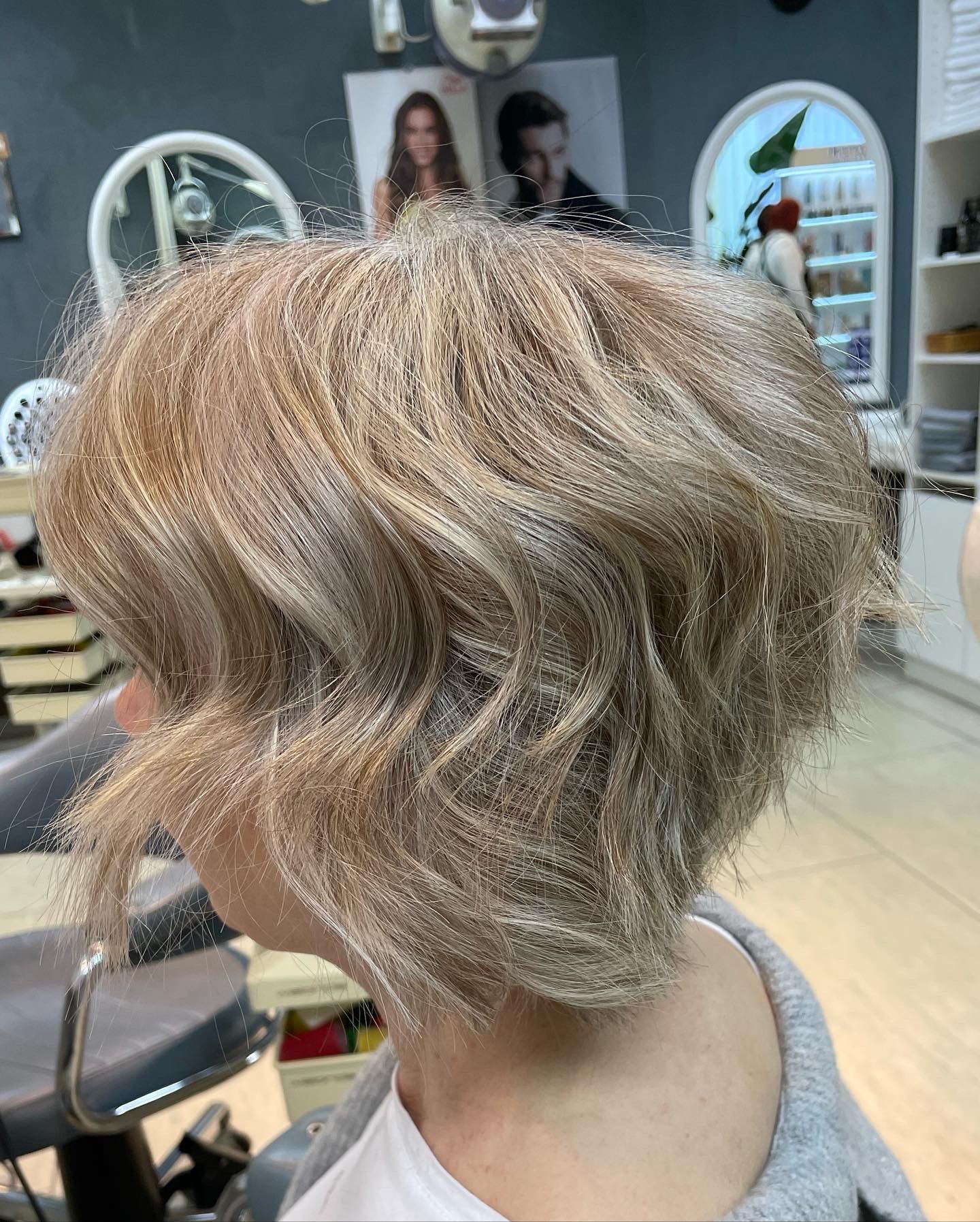 Frau mit welligem, hellbraunem Bob-Haarschnitt in einem Salon.