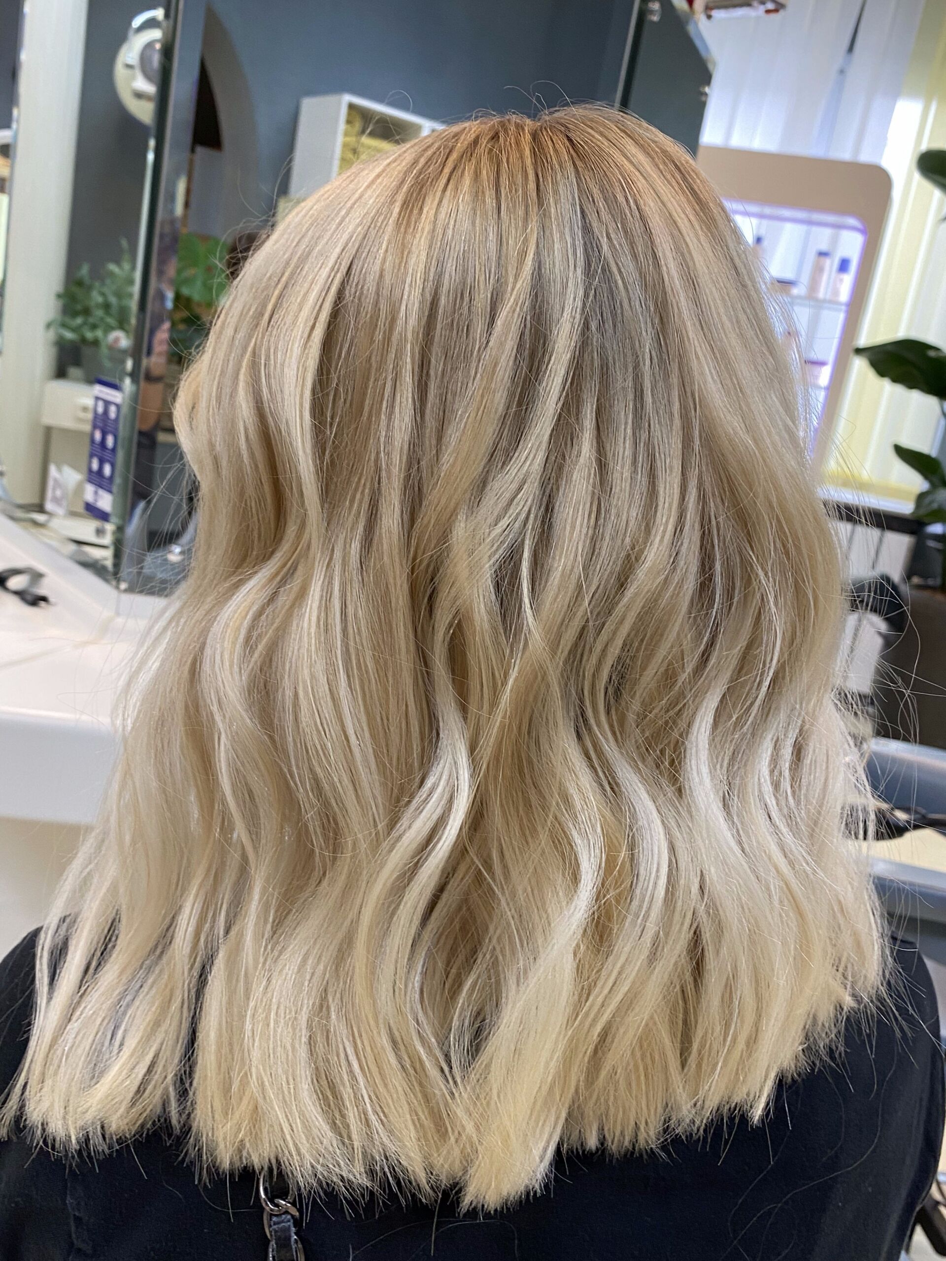 Frau mit welligem blondem Haar, gestylt in einem Salon.