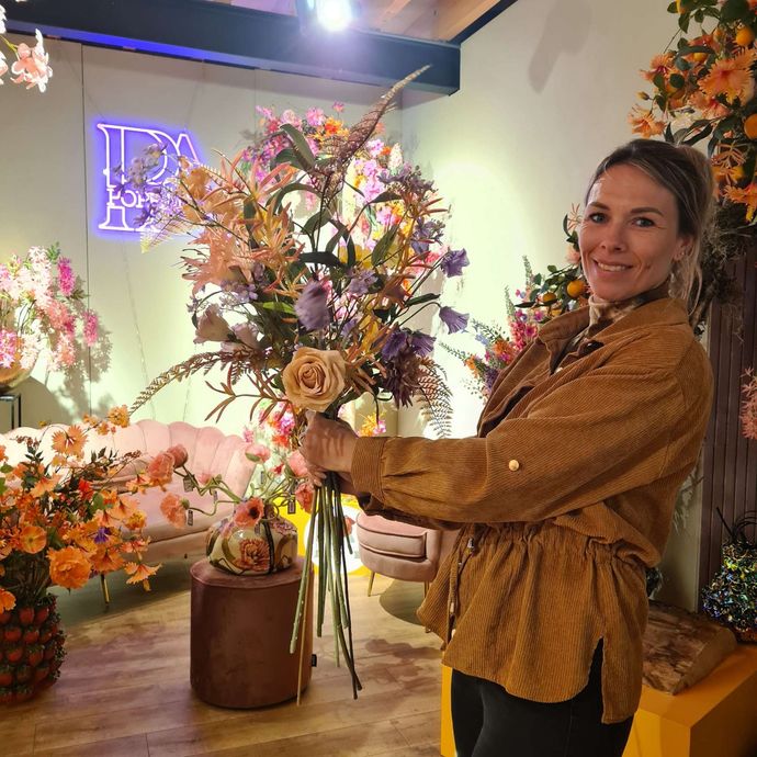 Een vaas gevuld met blauwe en gele bloemen staat op een tafel