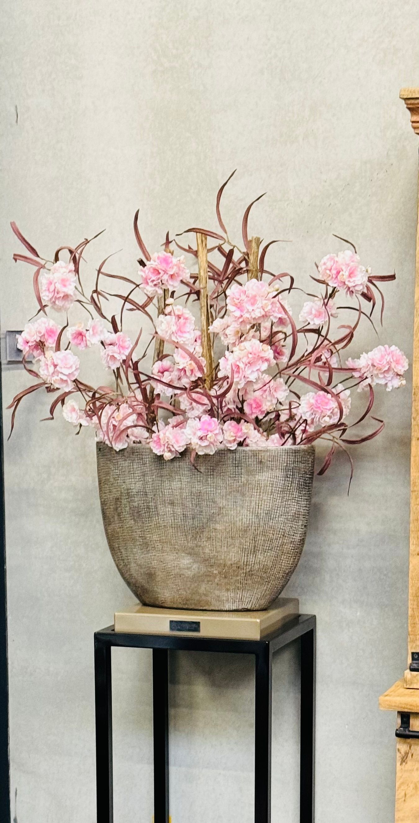 Op een tafel staat een vaas gevuld met roze bloemen.