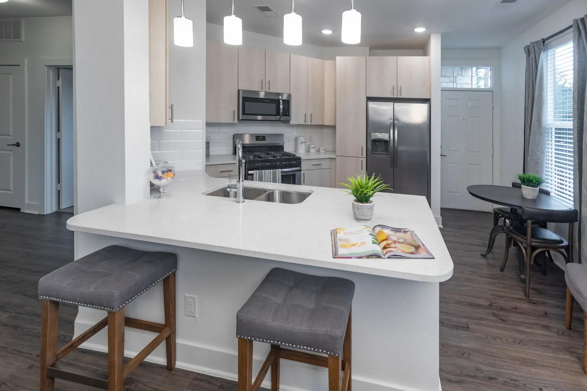 Modern kitchen with island, stainless steel appliances, and pendant lights.