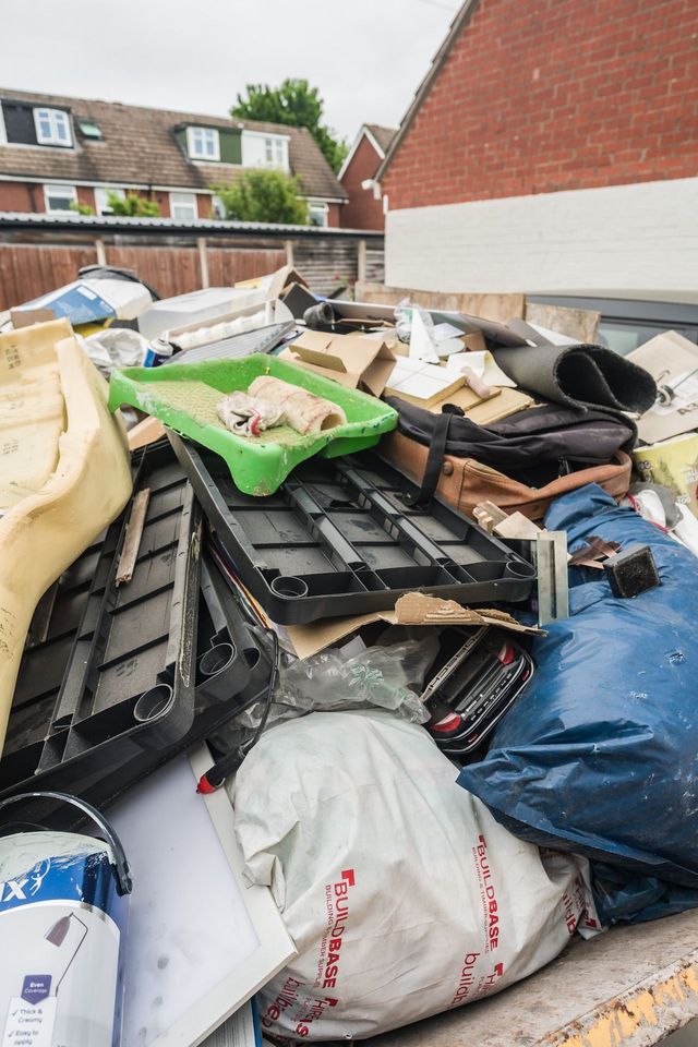 A pile of trash is sitting on top of a dumpster.