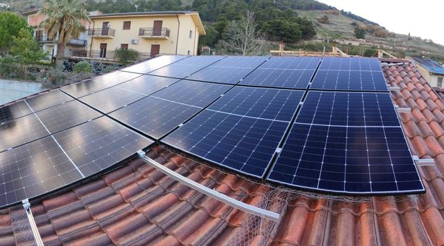 Pannelli solari installati su un tetto di tegole rosse in una zona residenziale collinare