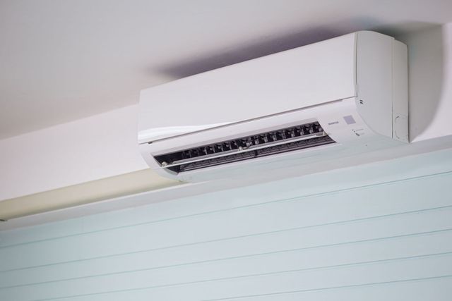 Condizionatore d'aria bianco a parete, installato sopra una parete interna di colore chiaro.