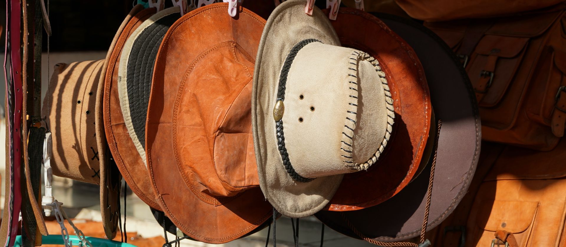 Hats of various colors hang on a line, with a tan hat in focus.