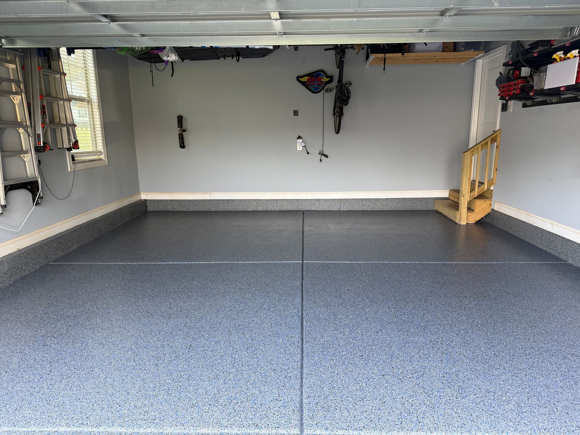 Empty garage with speckled epoxy floor and storage shelves on both sides