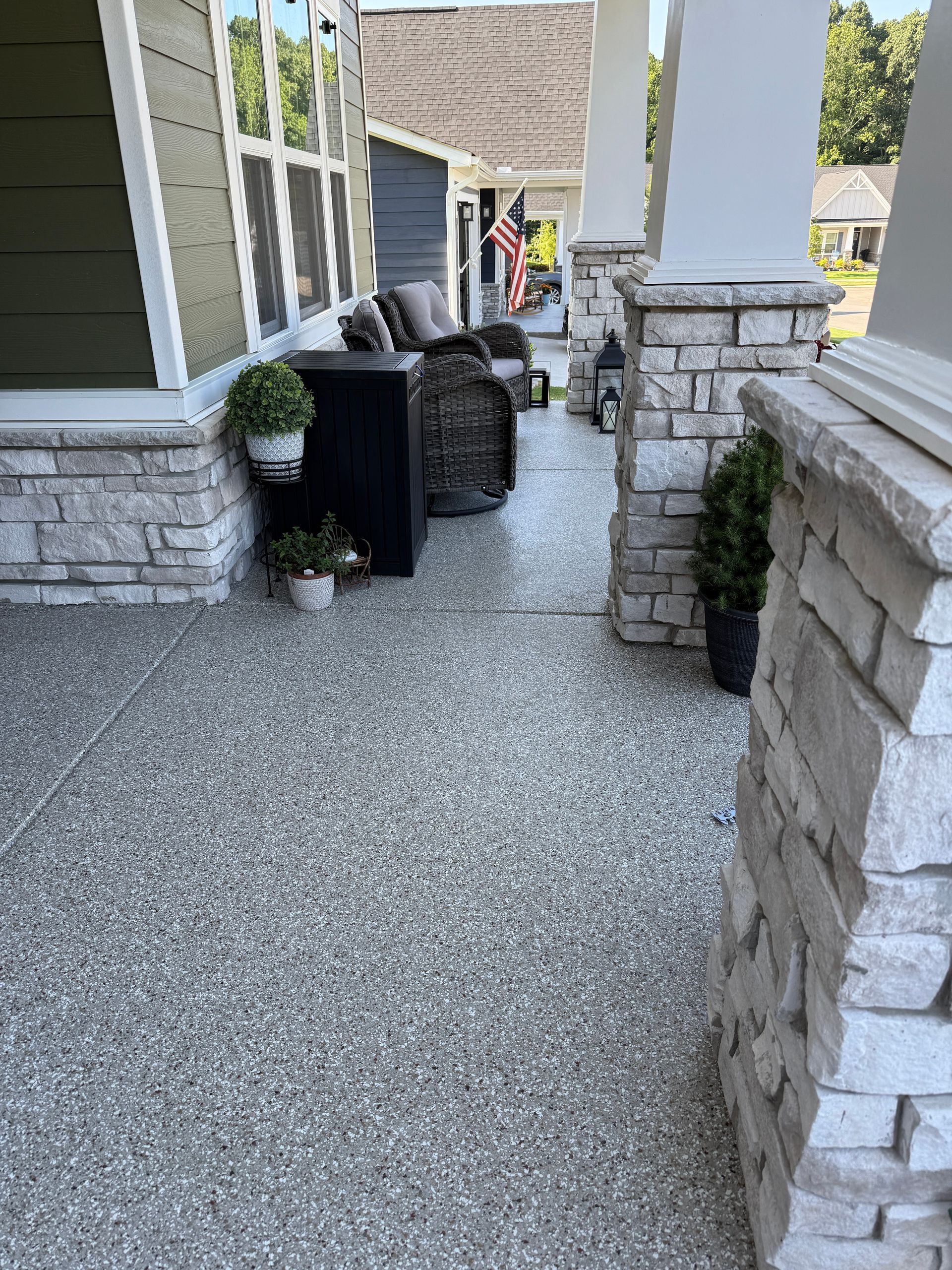 Stone front porch with stacked luggage and potted plants near a house entrance.