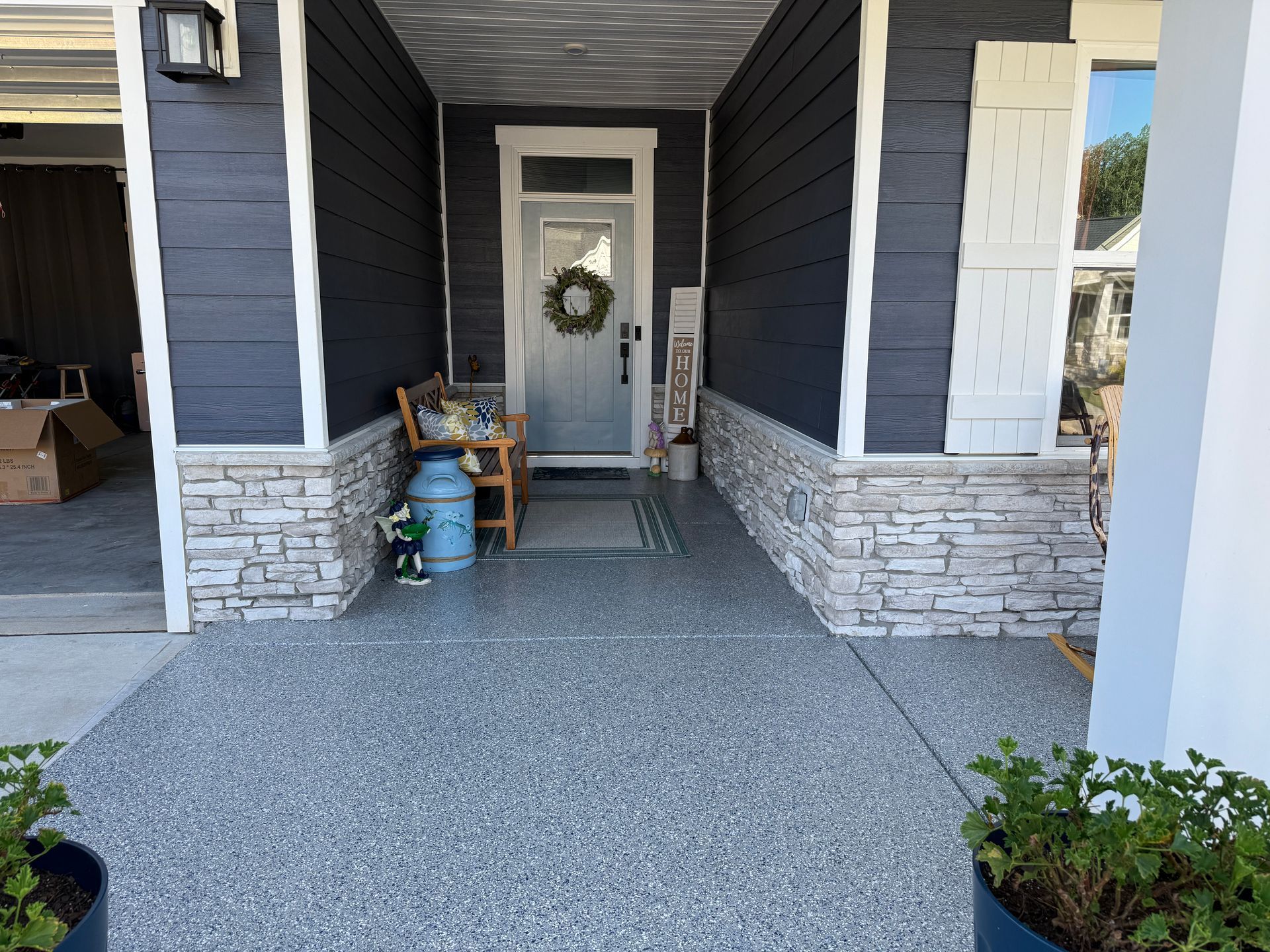 Front porch with gray stone walls, white door, and a pebbled walkway leading to the entrance