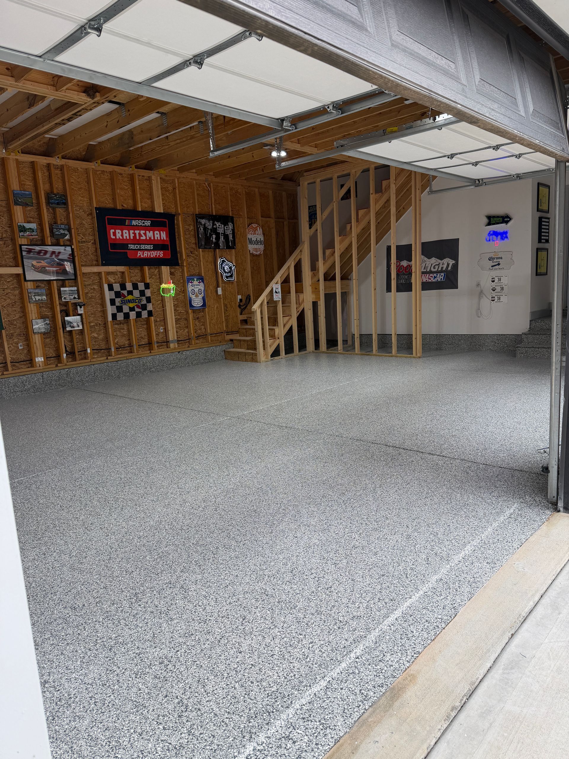 Gravel-covered parking area beside a wooden building with stairs and signs under an overhang