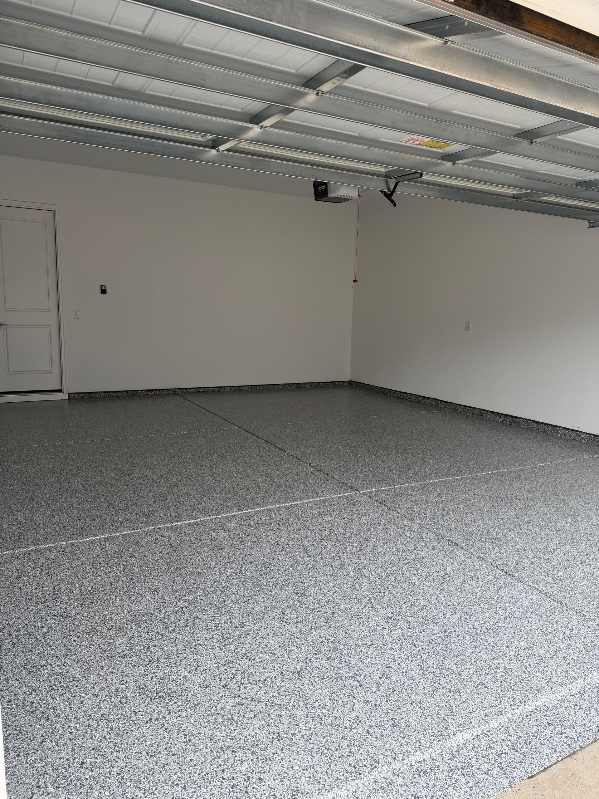 Empty garage with speckled epoxy floor and exposed ceiling beams