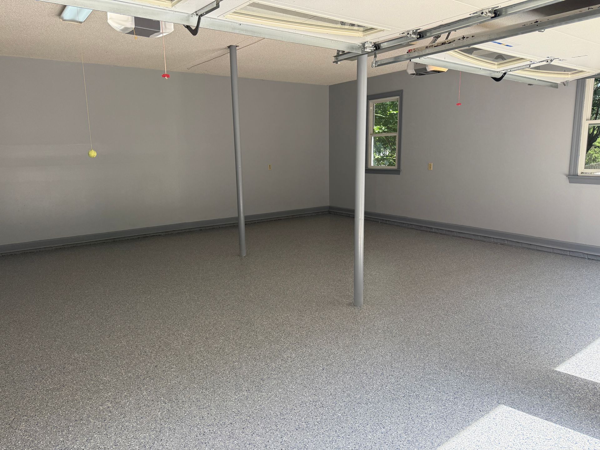Empty unfinished room with exposed ceiling, support posts, gray walls, and carpeted floor.