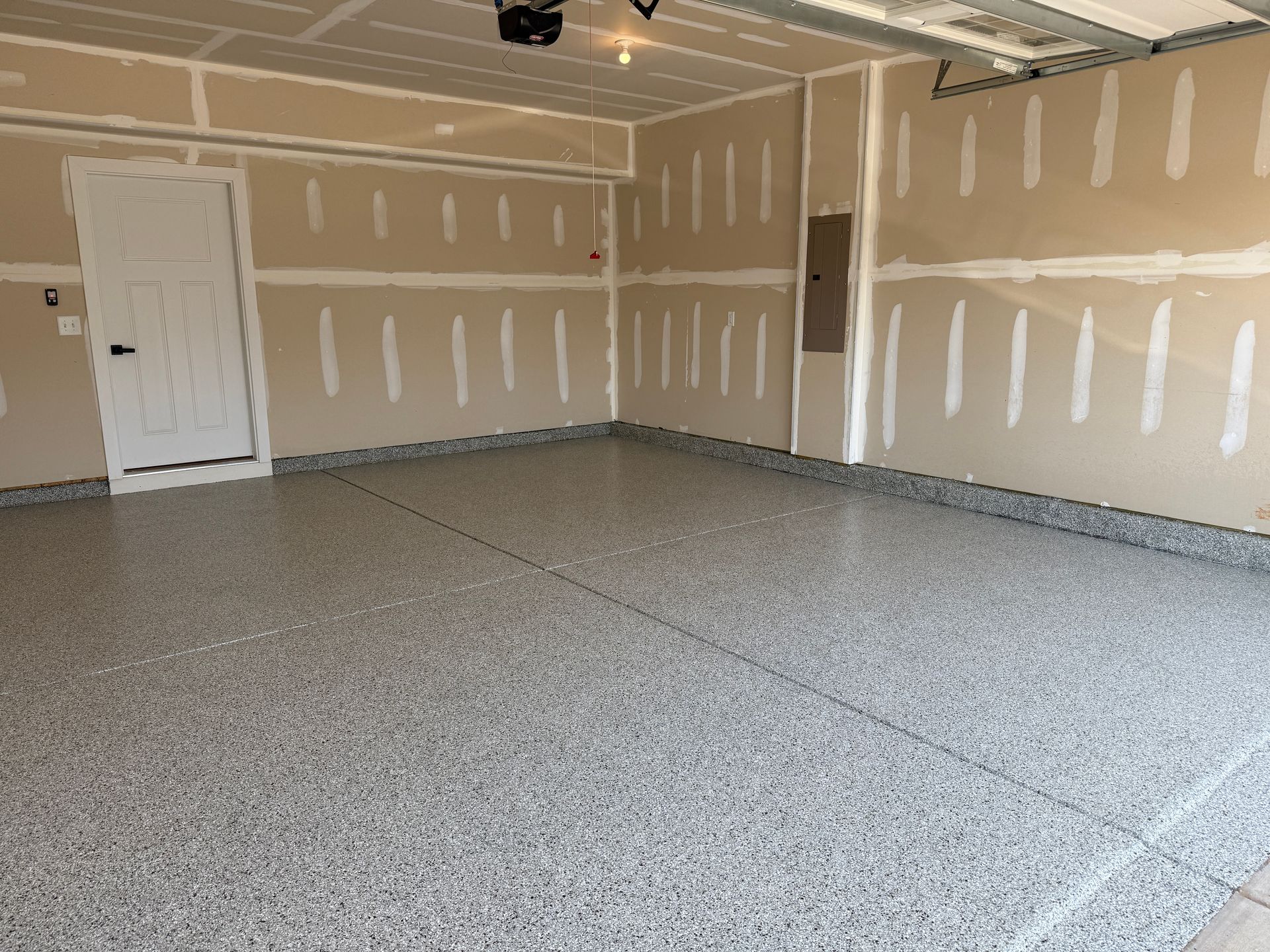 Empty unfinished garage with drywall, concrete floor, and a white side door