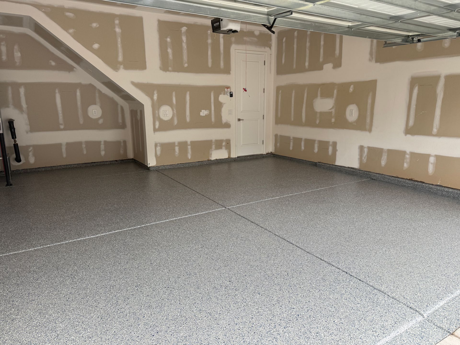 Empty unfinished garage with drywall, exposed ceiling beams, and concrete floor