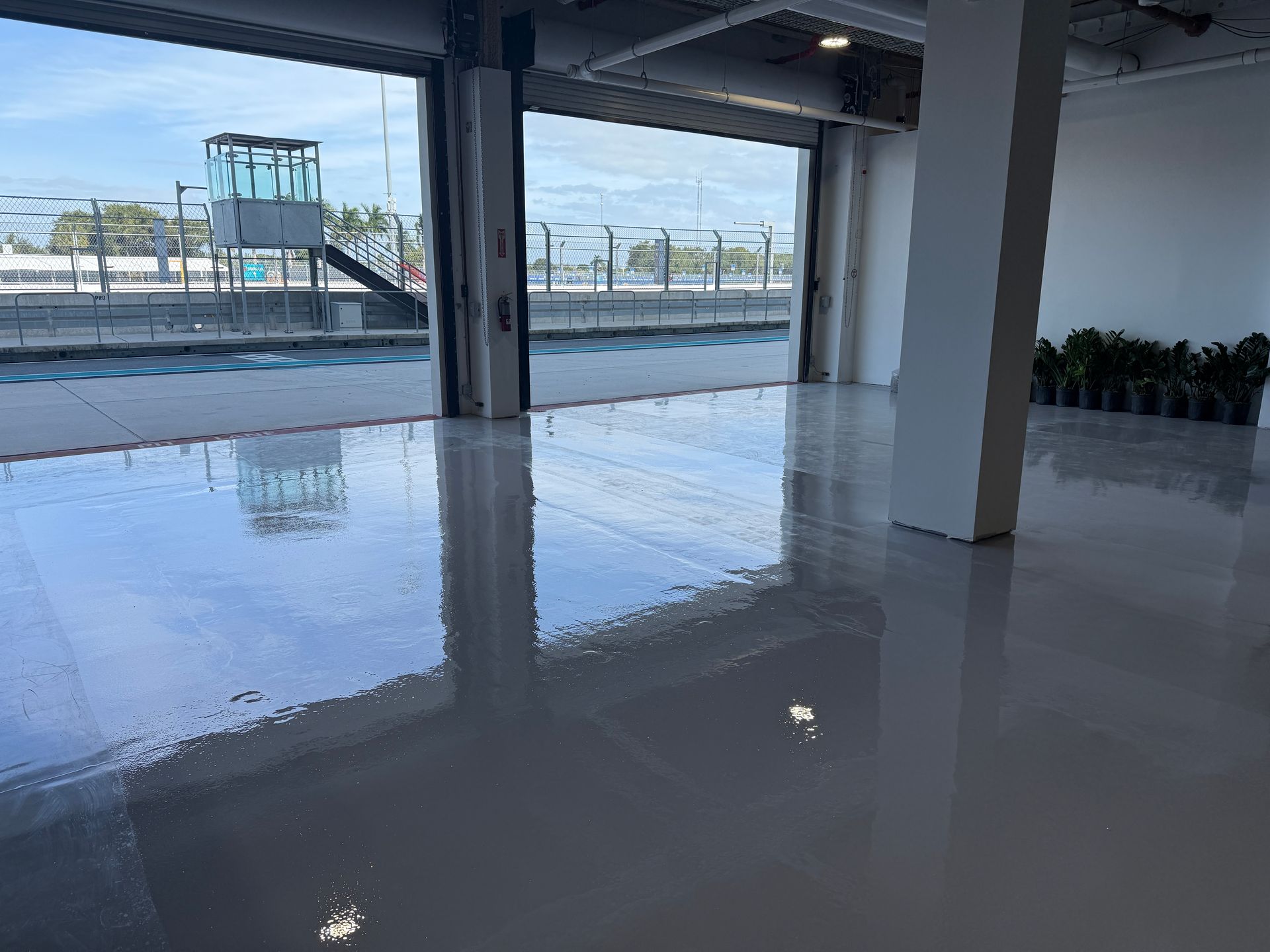 Empty indoor space with glossy white floor, open walls, and a waterfront view outside