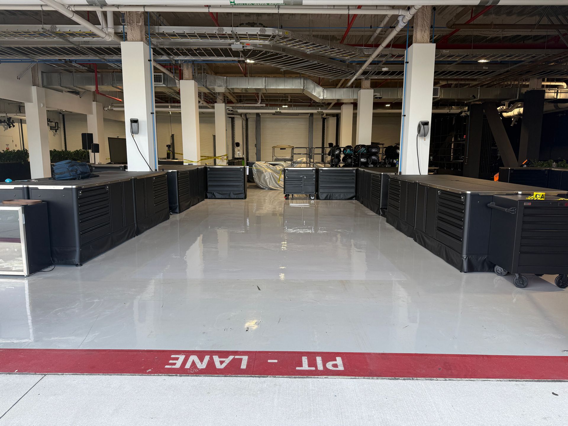 Empty industrial interior with black barriers and red “PIT LANE” marking on the floor