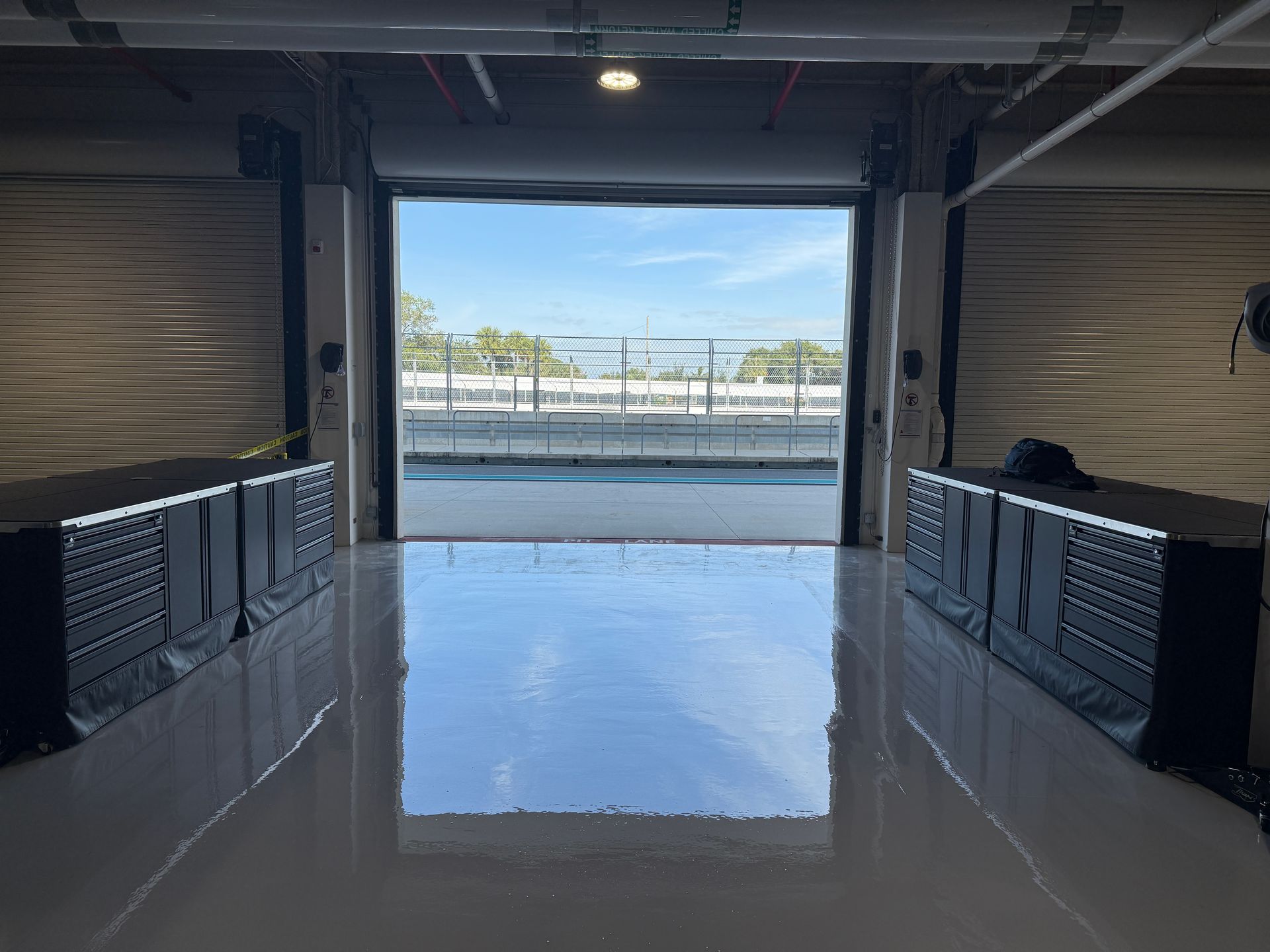 Empty garage opening onto a waterfront with glossy floor reflecting the bright outdoor view