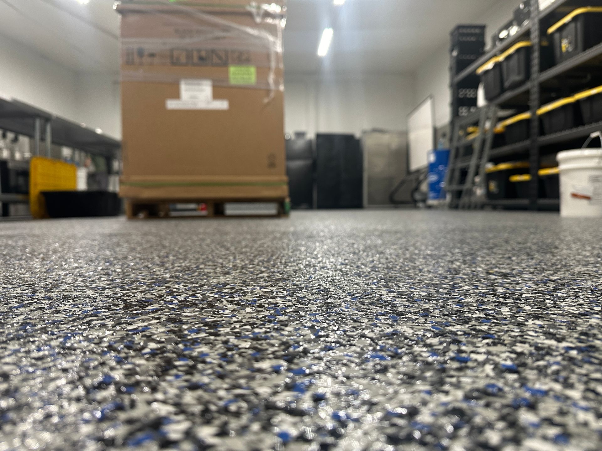 Low-angle view of a warehouse aisle with a palletized cardboard box and metal shelving racks on both sides