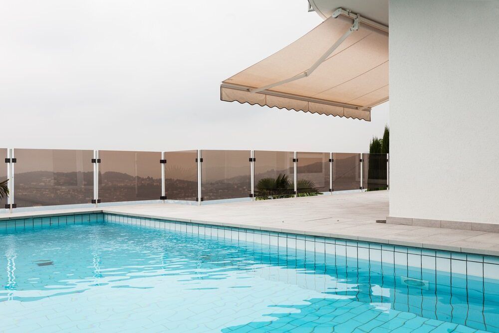 Pool With Turquoise Water, Beige Retractable Awning, and Safety Fence — Creative Pools and Spas in Mornington, VIC