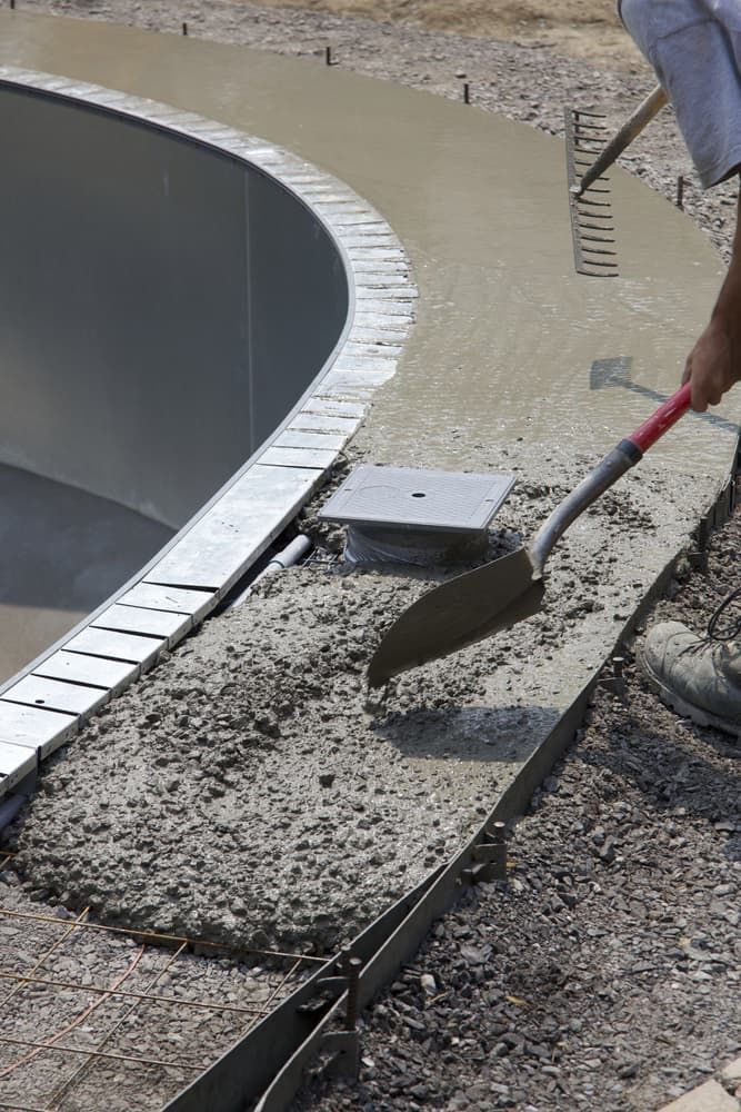 Man Shovels Concrete Into a Metal Form Alongside a Curved Skate Park Bowl — Creative Pools and Spas in Mount Martha, VIC