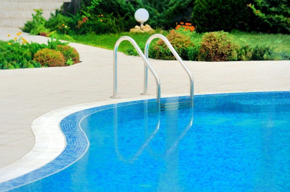 A Blue Pool With White Trim, Metal Ladder, and Surrounding Landscaping — Creative Pools and Spas in Melbourne, VIC
