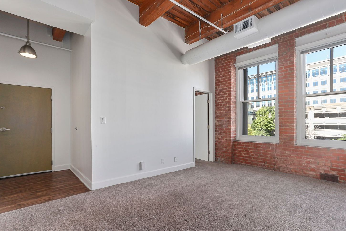 An empty room with a brick wall and a lot of windows.