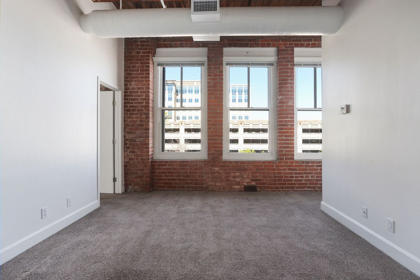 An empty room with a brick wall and a lot of windows