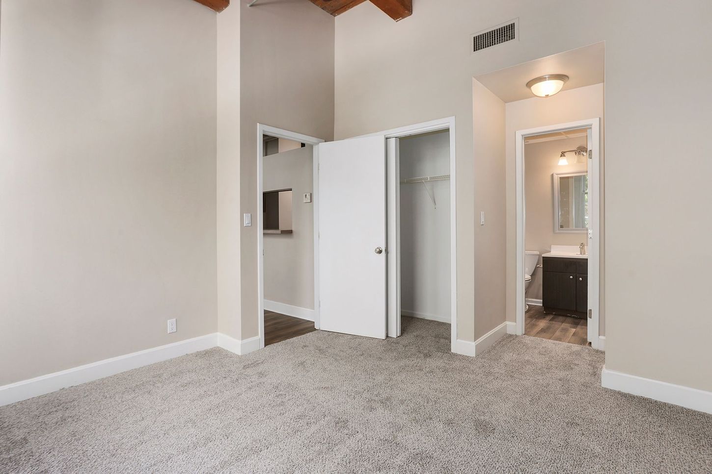An empty bedroom with a closet and a bathroom.