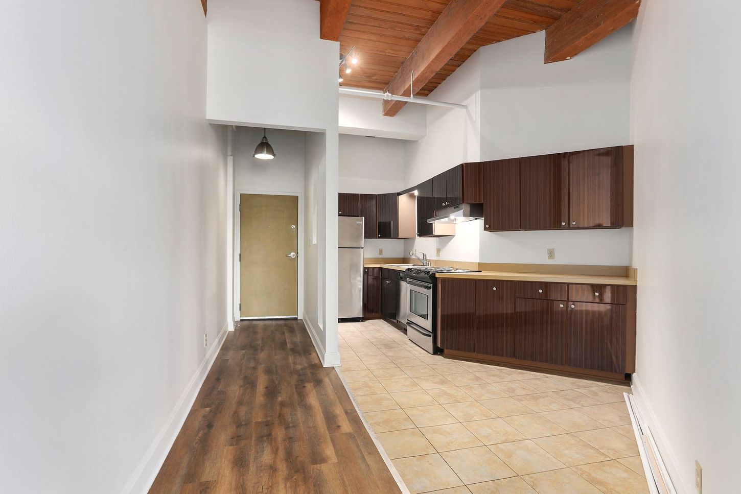 An empty kitchen with brown cabinets and a stove